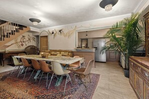Uma sala de jantar com uma mesa grande, cadeiras e um tapete estampado.