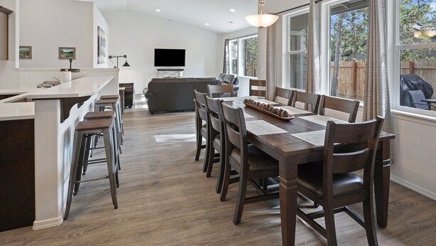 Une cuisine moderne avec un coin repas, un plancher en bois et de grandes fenêtres.
