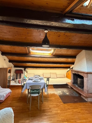 An attic dining area with a table set for four, a fireplace, and a skylight. - The Old Town Attic (Senigallia)