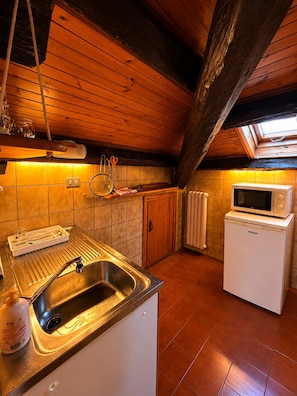Una cocina con un lavamanos, un microondas y una ventana.