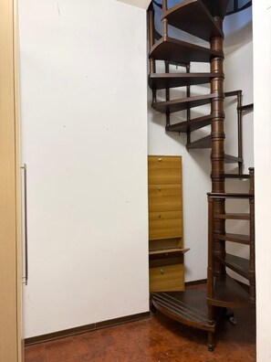 Un escalier en colimaçon dans une pièce avec une armoire en bois et une porte blanche.