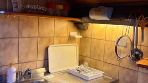 Een keuken met een spoelbak, een aanrecht en diverse keukengerei.