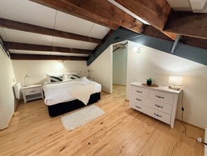 A bedroom with a bed, bedside tables, a dresser, a lamp, and a ceiling with exposed beams. - Stylish New York-Style Loft in Parnell  Spacious Auckland Escape with parking. (parnell)