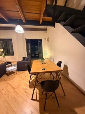 A modern interior with a wooden dining table, black chairs, a grey sofa, and a staircase. - Stylish New York-Style Loft in Parnell  Spacious Auckland Escape with parking. (parnell)