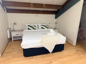Ein Schlafzimmer mit einem Bett, Nachttischen, einer Lampe und einem Bild an der Wand.