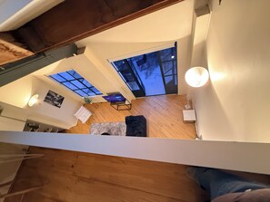 A high-ceilinged room with skylights, a wooden floor, a sofa, a table, and a lamp. - Stylish New York-Style Loft in Parnell  Spacious Auckland Escape with parking. (parnell)