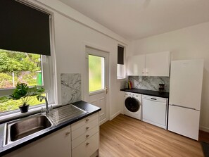 Une cuisine de taille réduite équipée d’un évier, d’un lave-linge et d’un réfrigérateur.