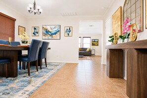A dining area with a table, chairs, and a chandelier. There are framed artworks on the walls and a rug on the floor. - Spacious North Austin–Pflugerville Retreat - 6 King Beds - Modern Comfort (Pflugerville)
