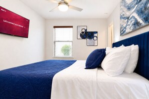 A bedroom with a bed, a ceiling fan, a TV, a window with blinds, and artwork on the wall. - Spacious North Austin–Pflugerville Retreat - 6 King Beds - Modern Comfort (Pflugerville)