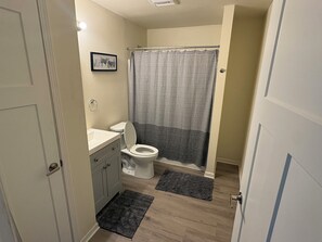Et badeværelse med toilet, håndvask og bruseforhæng.