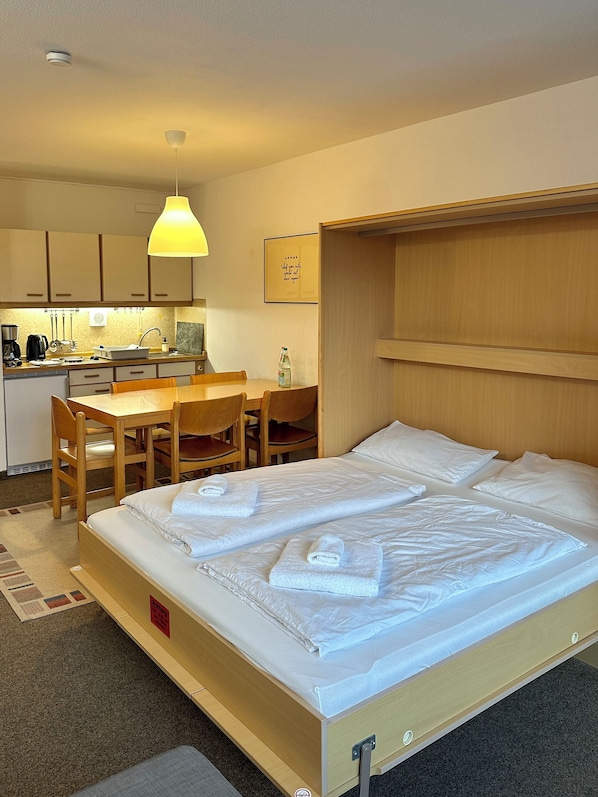 Une chambre d’hôtel avec un lit, un bureau et une kitchenette.