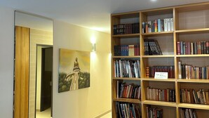 Une pièce avec une bibliothèque en bois, un tableau et une table en bois sur laquelle se trouvent un bol et des objets décoratifs.