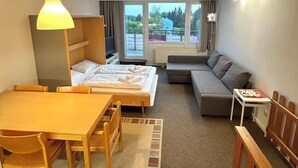 Une chambre d’hôtel de taille réduite, comprenant un lit, un canapé, une petite table et un téléviseur.