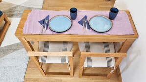 A wooden dining table with two chairs, a pink table runner, and two dark-colored cups. - Pittoresquia Paris Gare de l'Est (Paris)