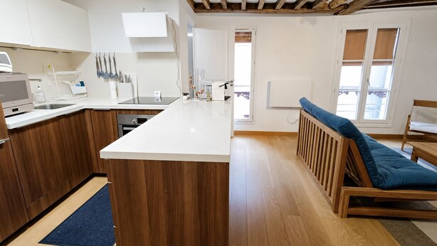 A modern kitchen with wooden cabinets, a white countertop, and a built-in oven. - Pittoresquia Paris Gare de l'Est (Paris)