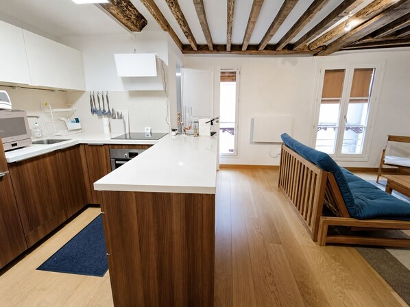 Eine moderne Küche mit Holzschränken, einer weißen Arbeitsplatte und einem eingebauten Backofen.