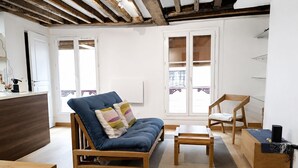 A modern living room with a sofa, a wooden chair, a small table, and a wooden bench. - Pittoresquia Paris Gare de l'Est (Paris)