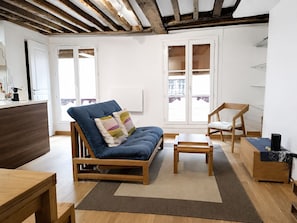 Ein modernes Wohnzimmer mit einer Couch, einem Holzstuhl, einem kleinen Tisch und einer Holzbank.
