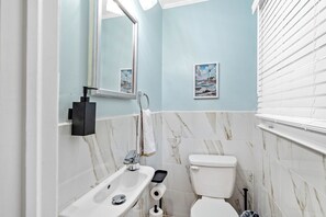 Ein Badezimmer mit Toilette, Waschbecken, Spiegel und zwei Bildern an der Wand.
