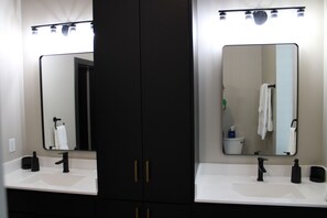 A bathroom with two sinks, a large mirror, and a dark cabinet. - Bird's Eye View of Stanton (Stanton)