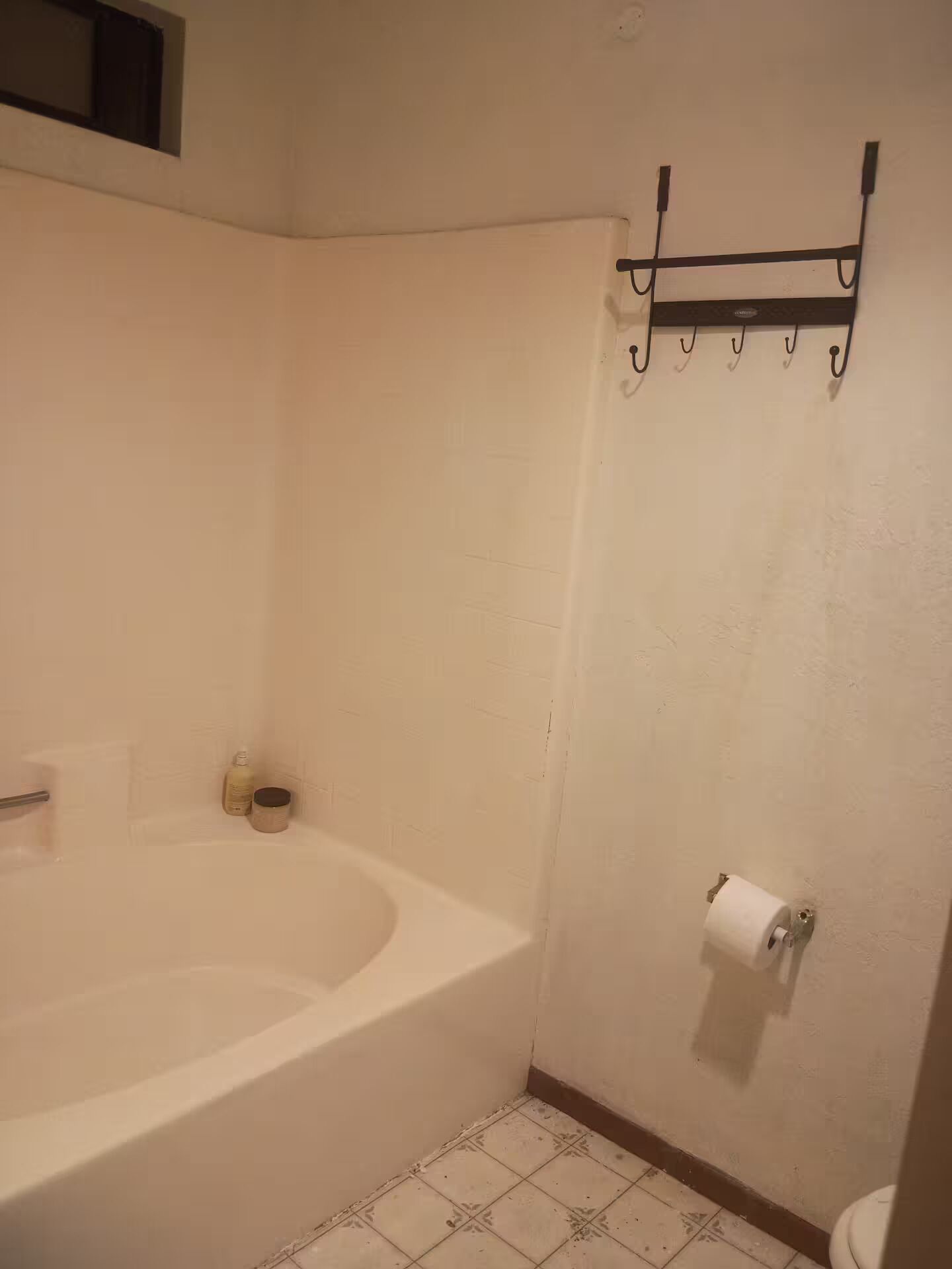 A bathroom with a bathtub, toilet, and a towel rack.