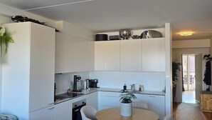 Eine moderne Küche mit weißen Schränken, einem Esstisch mit Stühlen und einer kleinen Kochinsel.