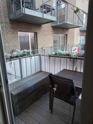 Un balcon avec un banc en bois, une chaise et des plantes en pot.