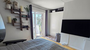 Ein modernes Schlafzimmer mit einem großen Bett, integrierten Regalen, einem Fernseher und einer Glastür zum Außenbereich.