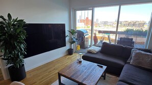 Ein modernes Wohnzimmer mit Flachbildfernseher, einer Couch, einem Couchtisch und einer Topfpflanze.