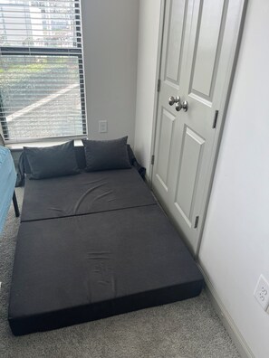 Um quarto com uma cama, uma porta e uma janela.