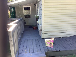 A wooden deck with a railing, a potted plant, and a hanging light fixture. - Soothing 1-bedroom cottage with AC in charming Clyde.  Located on quiet 5 acres (Clyde)