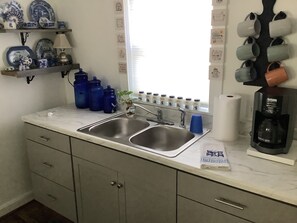 A kitchen with two sinks, a coffee maker, and a window with blinds. - Soothing 1-bedroom cottage with AC in charming Clyde.  Located on quiet 5 acres (Clyde)