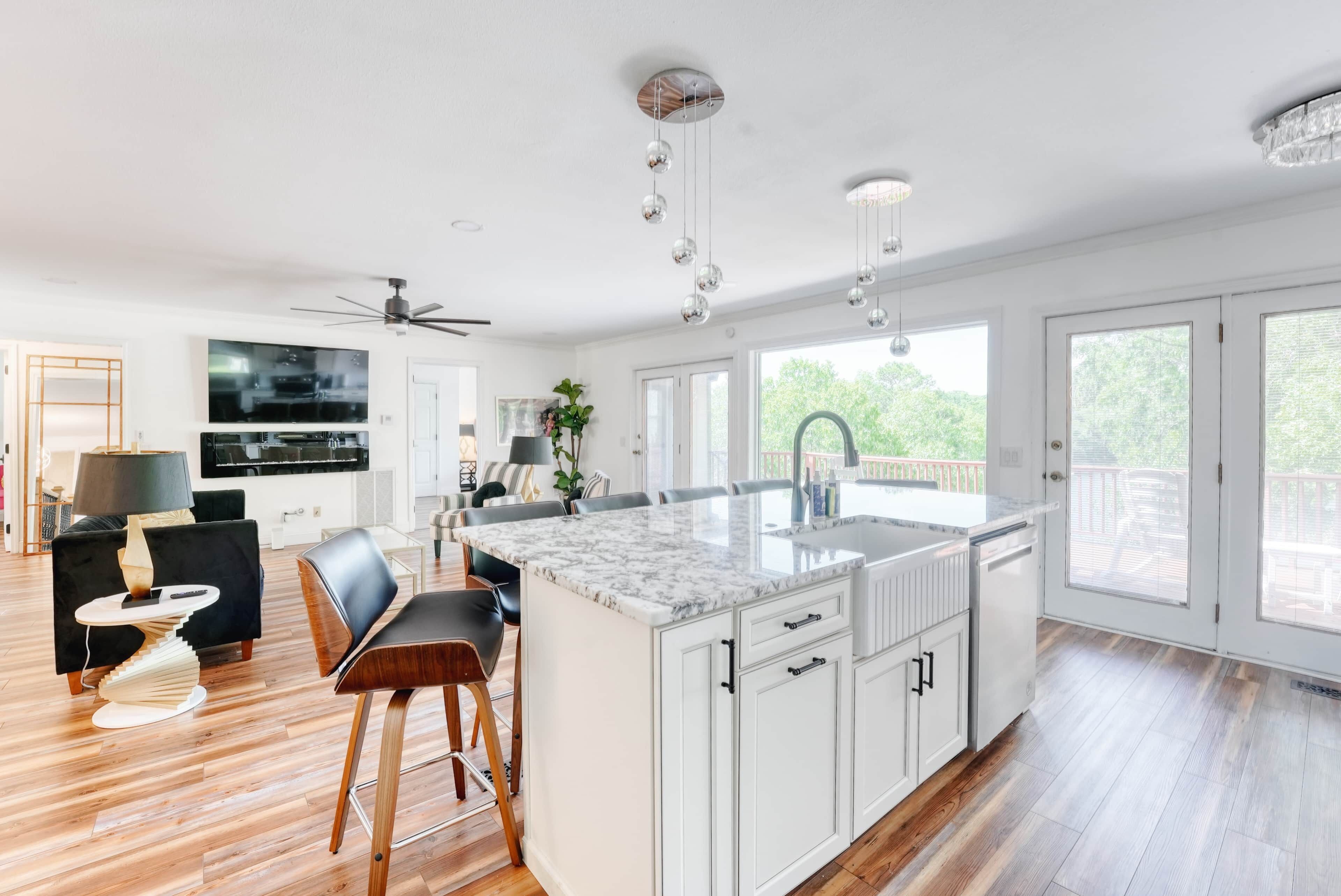 Una cocina amplia con una isla grande, muebles blancos y vistas al exterior.