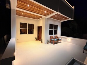 Une maison moderne dotée d’un vaste patio, d’un plafond en bois et de grandes fenêtres.