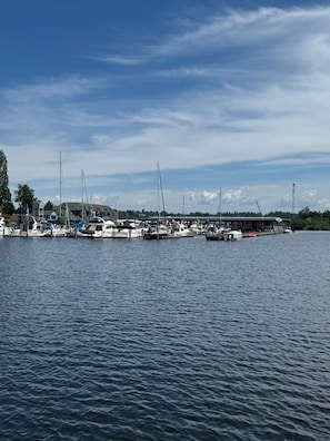 Ein Hafen mit mehreren vertäuten Booten, ein Gebäude mit Gründach und klarer Himmel.