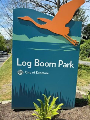 Schild für den Log Boom Park mit einer VogelSilhouette und einer Berglandschaft.
