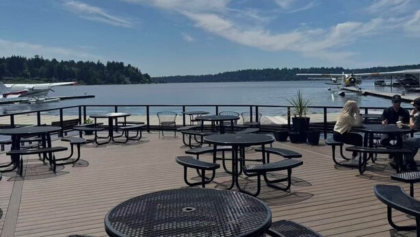 Een terras met buitentafels en stoelen met uitzicht op een waterpartij.