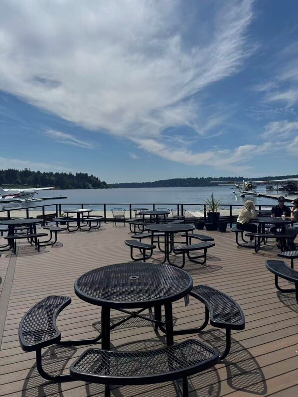Eine Terrasse mit Außenbestuhlung und Blick auf ein Gewässer.