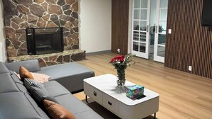 Een moderne woonkamer met een stenen muur, een grijze bank, een witte salontafel en een open haard.
