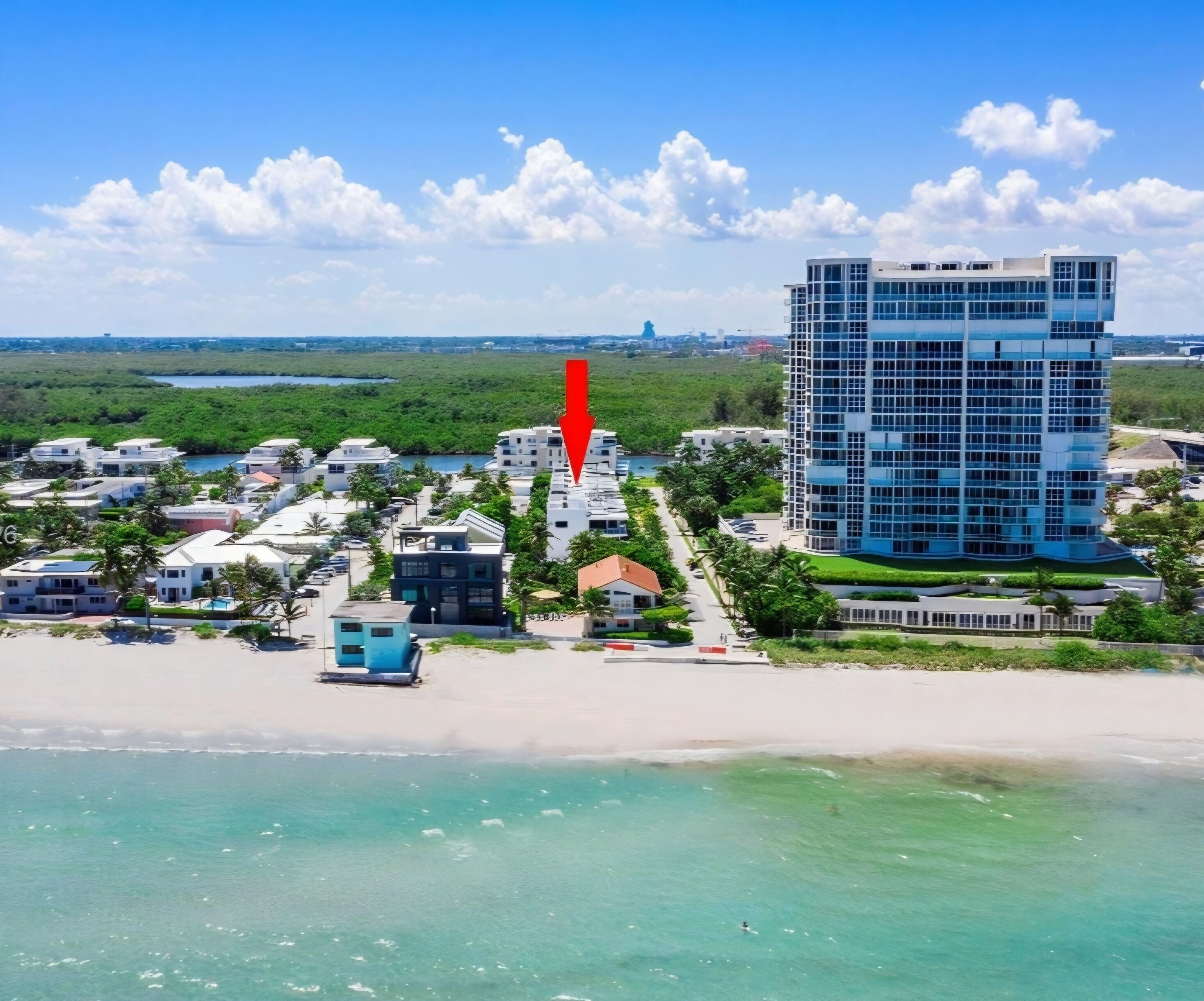 Zona residencial costeira com edifícios modernos, uma praia e um céu limpo.