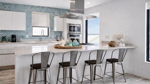 A modern kitchen with a central island, stainless steel appliances, and a view to the outside. - Beautiful beachfront villa (Hollywood)