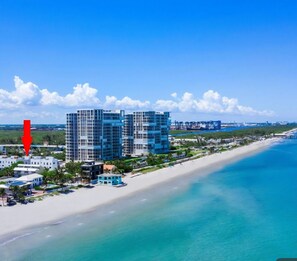 Ein Küstenhotel mit mehreren Hochhäusern, einem Strandzugang und einem wolkenlosen, blauen Himmel.