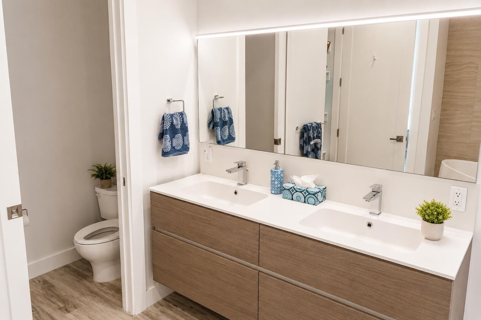 Un bagno moderno con un lavandino bianco, due portasci, un water e uno specchio.
