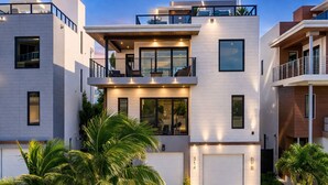 A modern multi-story residential building with a balcony, large windows, and a driveway. - Beautiful beachfront villa (Hollywood)