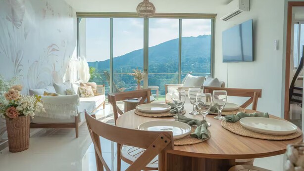 Uma área de refeições com vista para montanhas, uma janela grande e uma televisão de tela plana na parede.