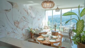 Uma área de jantar com uma mesa posta para quatro pessoas, uma janela grande com vista para as montanhas e um lustre.