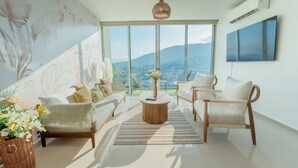 Uma sala de estar moderna com sofá, cadeiras, uma mesa de centro e uma grande janela com vista para uma montanha.