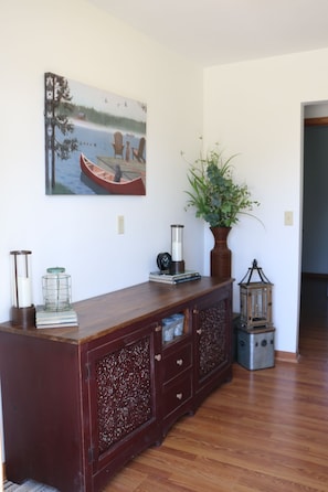 A wooden cabinet with drawers, a potted plant, a wall-mounted painting, and a small lantern on the floor. - Charming 4 Bedroom Home in Waucoma, Iowa-River front property (Waucoma)
