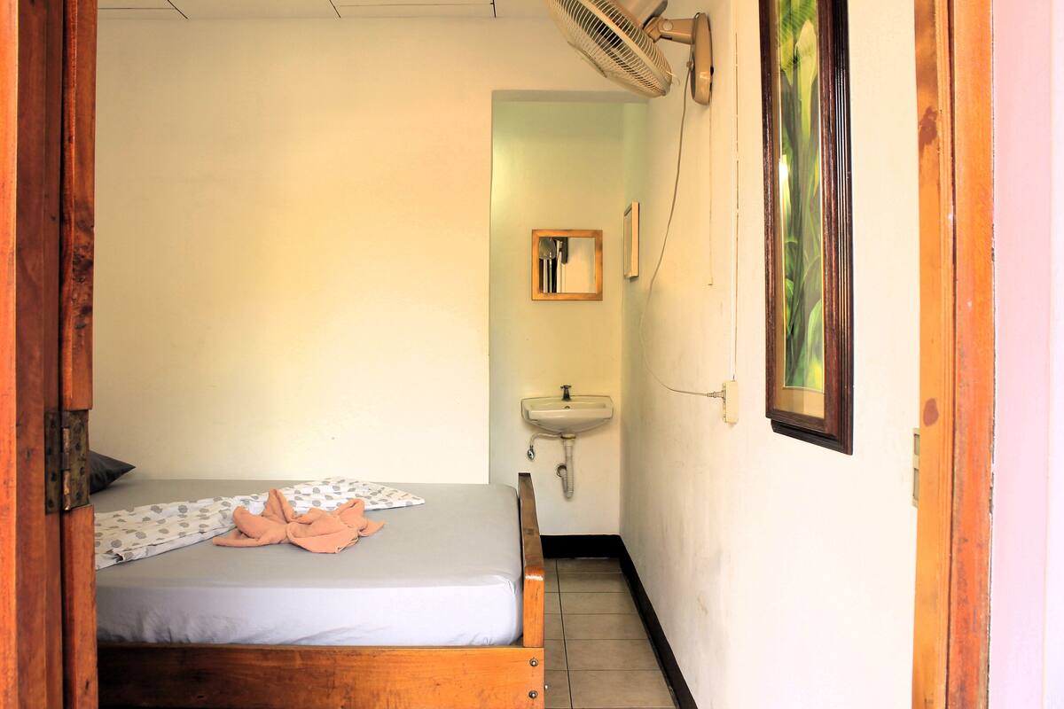 A small room with a bed, a sink, and a mirror.