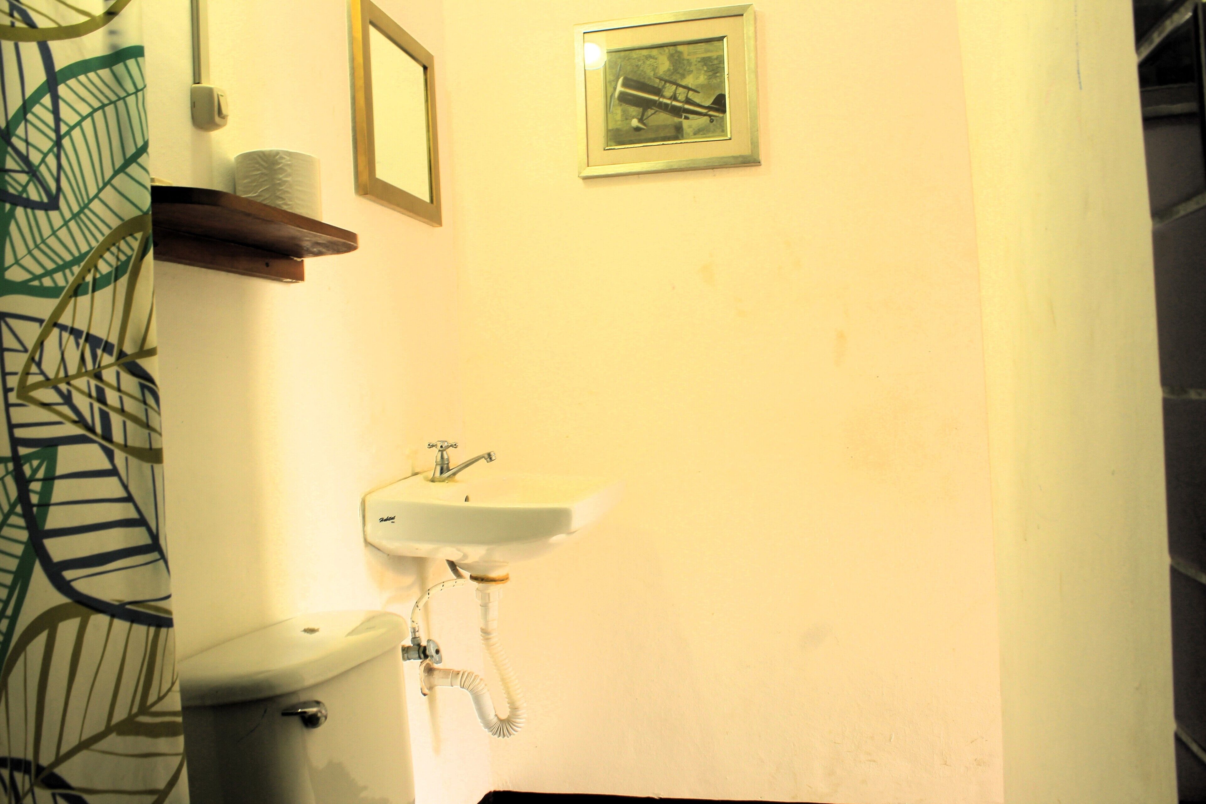A bathroom with a toilet, sink, and a framed picture on the wall.
